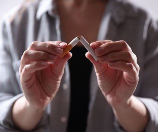 Photo of Woman holding broken cigarette, closeup. Stop smoking