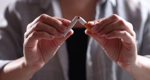 Photo of Woman holding broken cigarette, closeup. Stop smoking