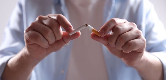 Photo of Man holding broken cigarette, closeup. Stop smoking