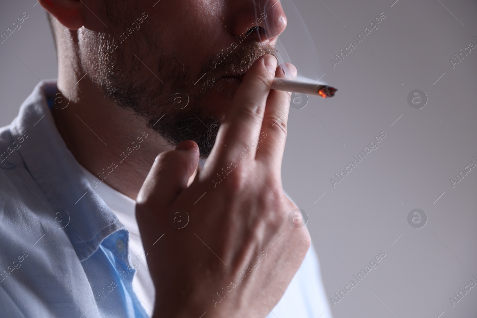 Man smoking cigarette on light background, closeup Photo of Man smoking cigarette on light background, closeup