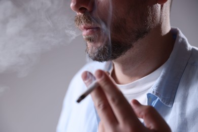 Photo of Man smoking cigarette on light background, closeup