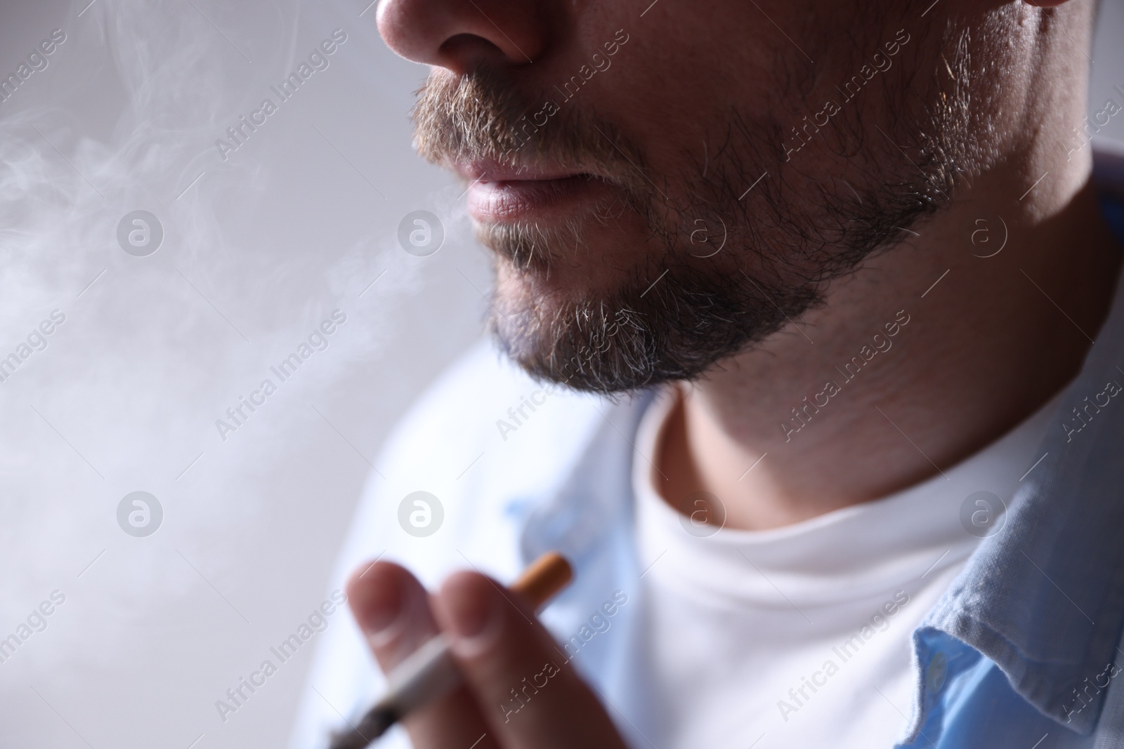Man smoking cigarette on light background, closeup Photo of Man smoking cigarette on light background, closeup