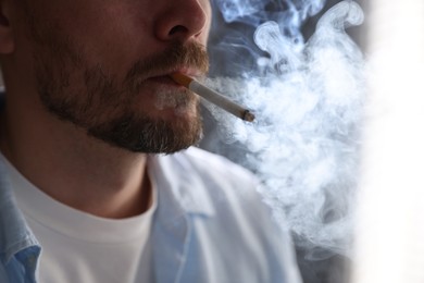 Photo of Man smoking cigarette on blurred background, closeup