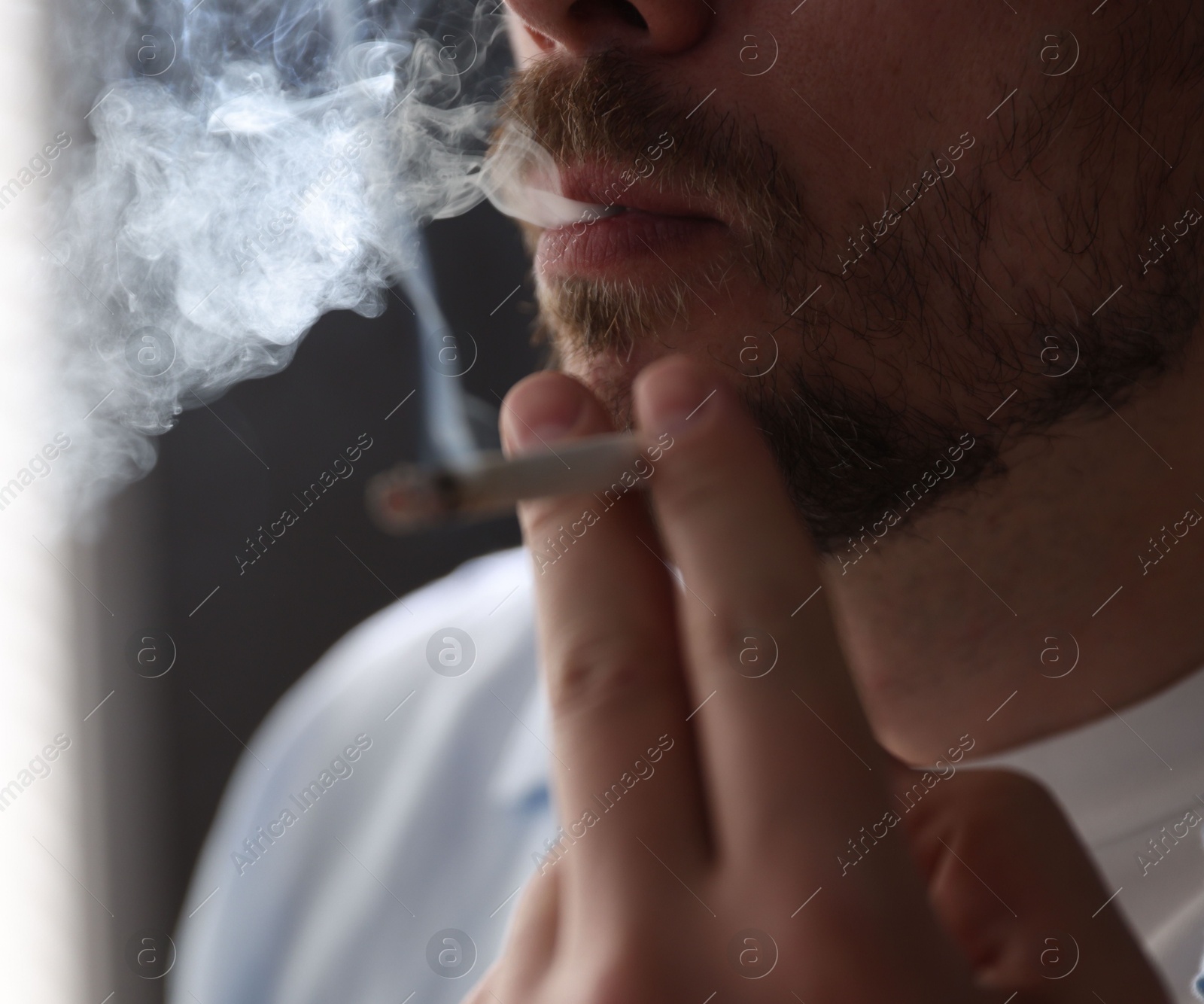 Man smoking cigarette on blurred background, closeup Photo of Man smoking cigarette on blurred background, closeup