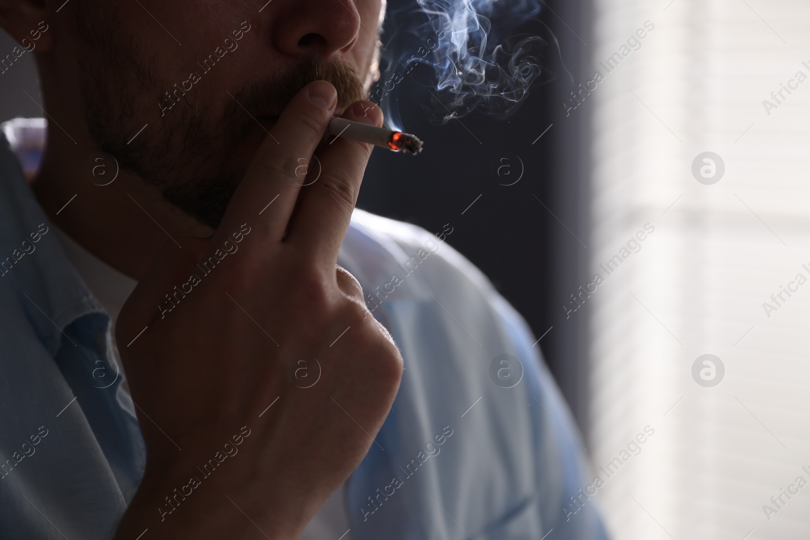 Man smoking cigarette on blurred background, closeup Photo of Man smoking cigarette on blurred background, closeup