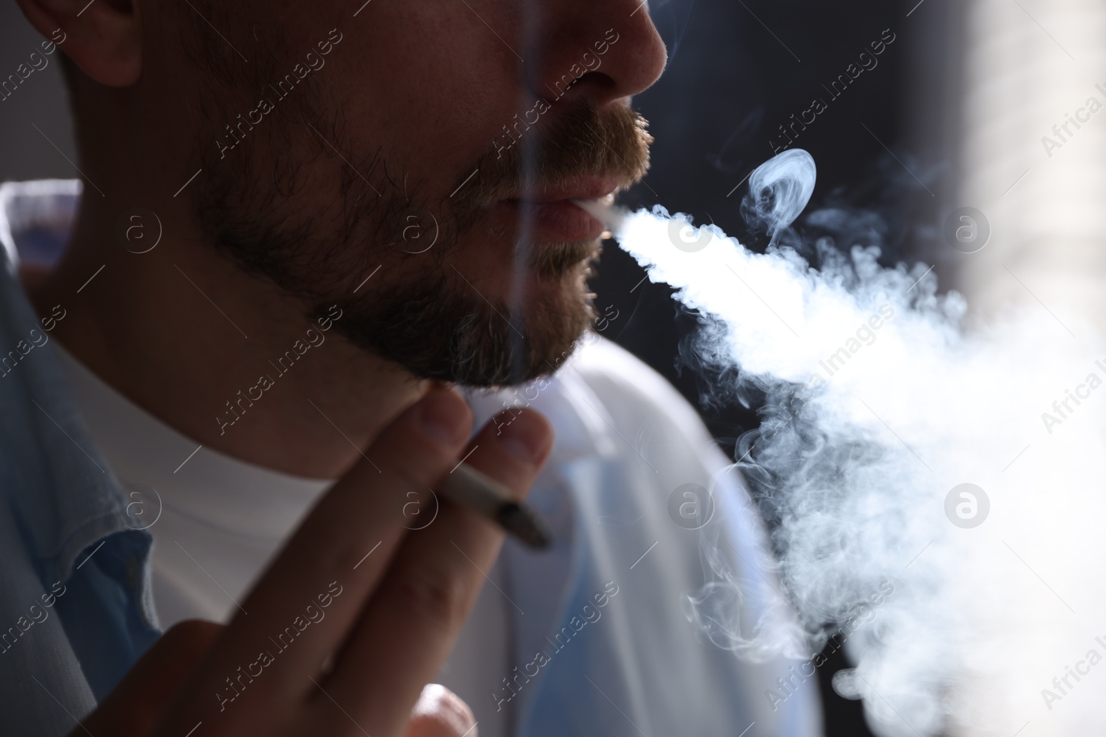 Man smoking cigarette on blurred background, closeup Photo of Man smoking cigarette on blurred background, closeup