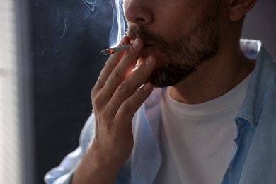 Photo of Man smoking cigarette on blurred background, closeup