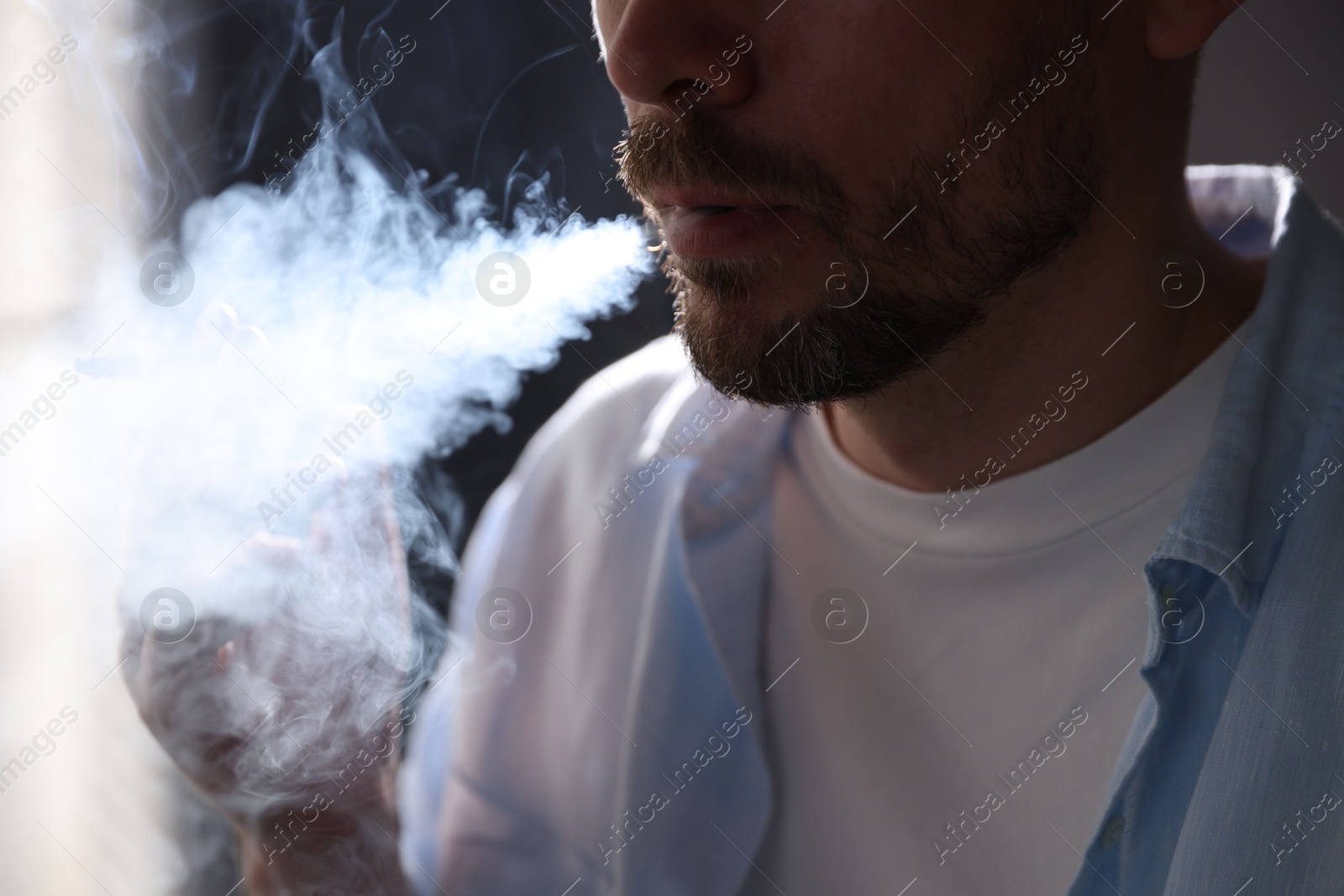 Man smoking cigarette on blurred background, closeup Photo of Man smoking cigarette on blurred background, closeup