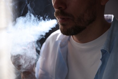 Photo of Man smoking cigarette on blurred background, closeup