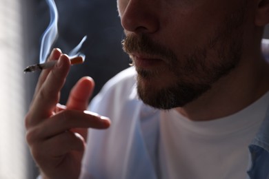 Photo of Man smoking cigarette on blurred background, closeup