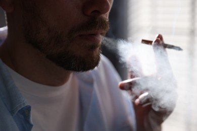 Photo of Man smoking cigarette on blurred background, closeup