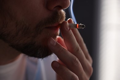 Photo of Man smoking cigarette on blurred background, closeup