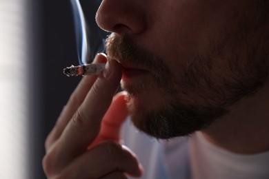 Photo of Man smoking cigarette on blurred background, closeup