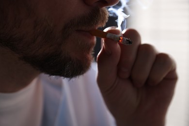 Photo of Man smoking cigarette on blurred background, closeup