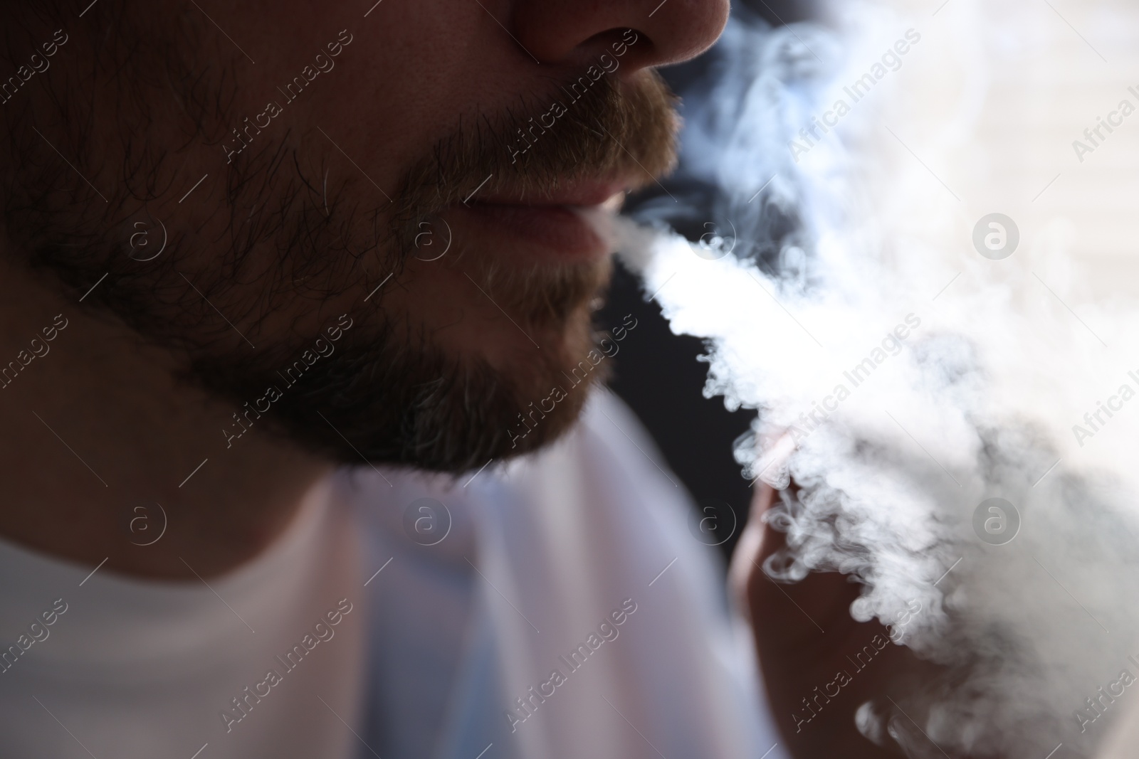 Man smoking cigarette on blurred background, closeup Photo of Man smoking cigarette on blurred background, closeup