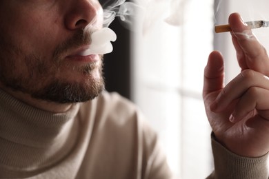 Photo of Man smoking cigarette on blurred background, closeup
