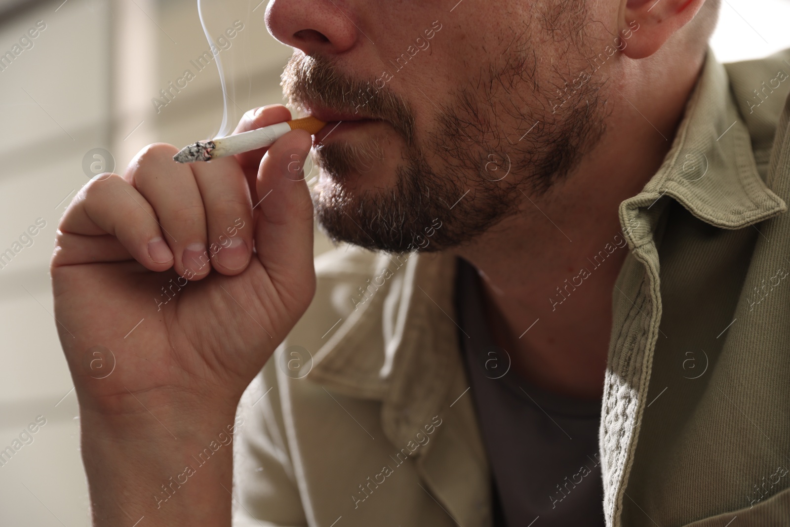 Man smoking cigarette on blurred background, closeup Photo of Man smoking cigarette on blurred background, closeup