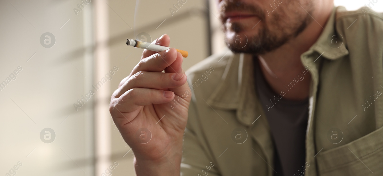 Man smoking cigarette on blurred background, closeup. Space for text Photo of Man smoking cigarette on blurred background, closeup. Space for text