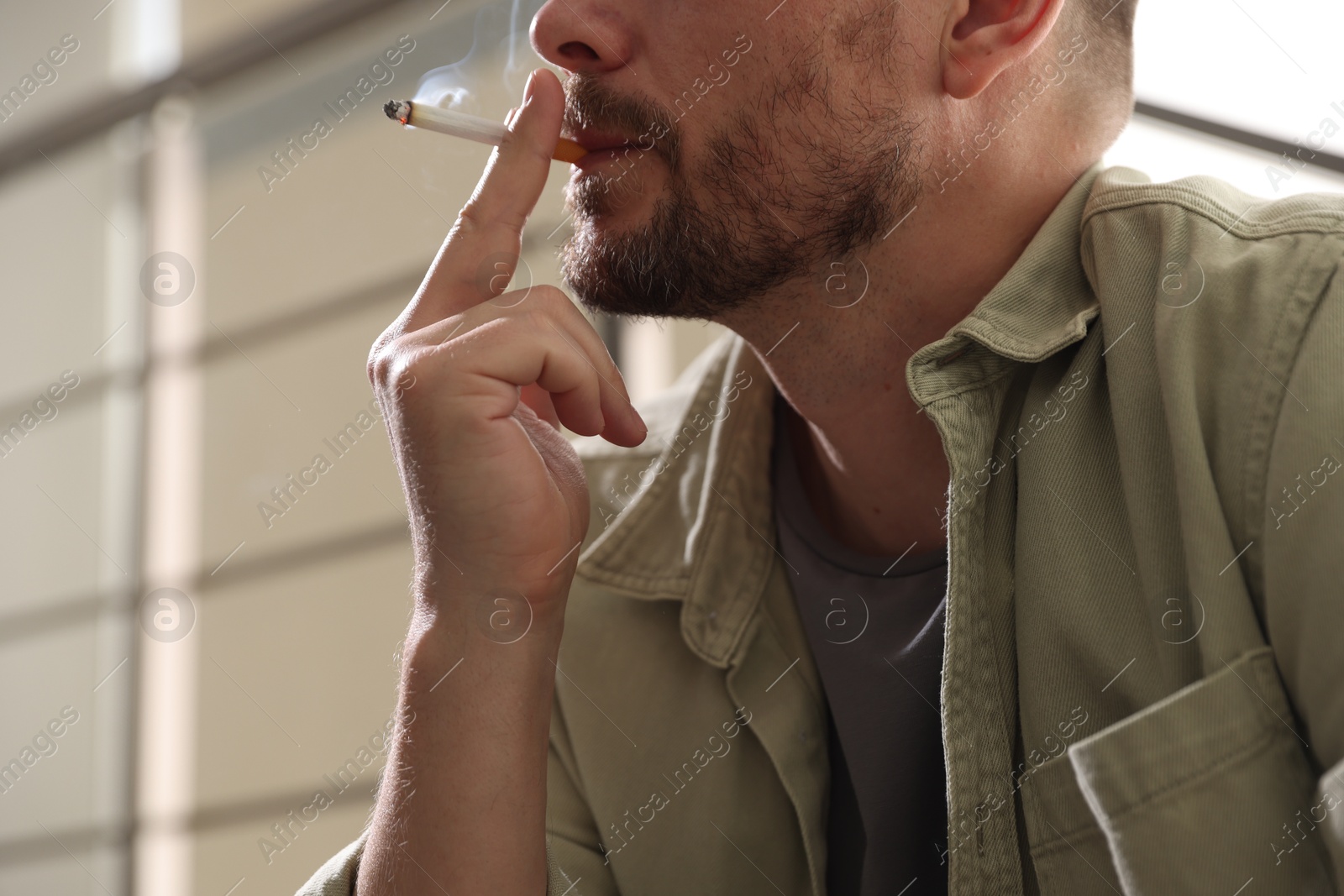 Man smoking cigarette on blurred background, closeup Photo of Man smoking cigarette on blurred background, closeup