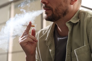 Photo of Man smoking cigarette on blurred background, closeup