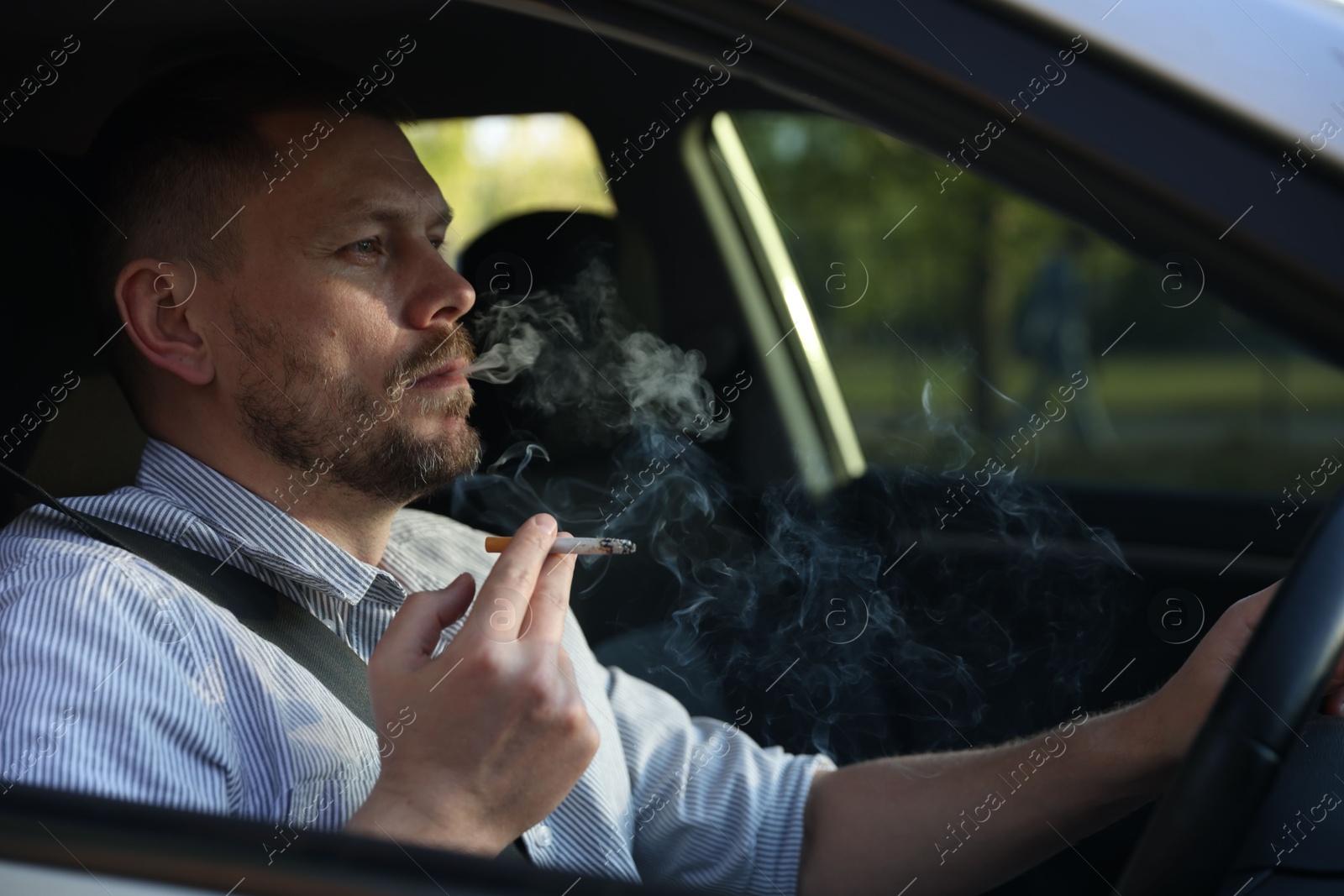 Man smoking cigarette in car, view from outside Photo of Man smoking cigarette in car, view from outside