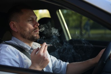 Photo of Man smoking cigarette in car, view from outside