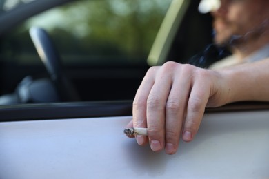 Photo of Man smoking while driving in car, focus on cigarette. Space for text