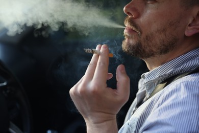 Photo of Man smoking cigarette in car, closeup. Space for text