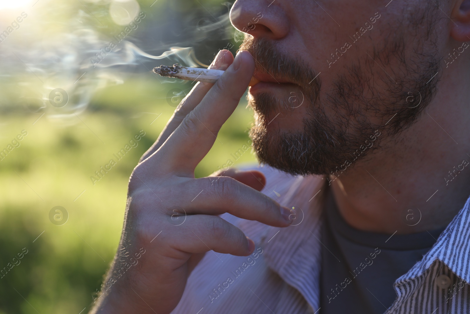 Man smoking cigarette on blurred background, closeup Photo of Man smoking cigarette on blurred background, closeup