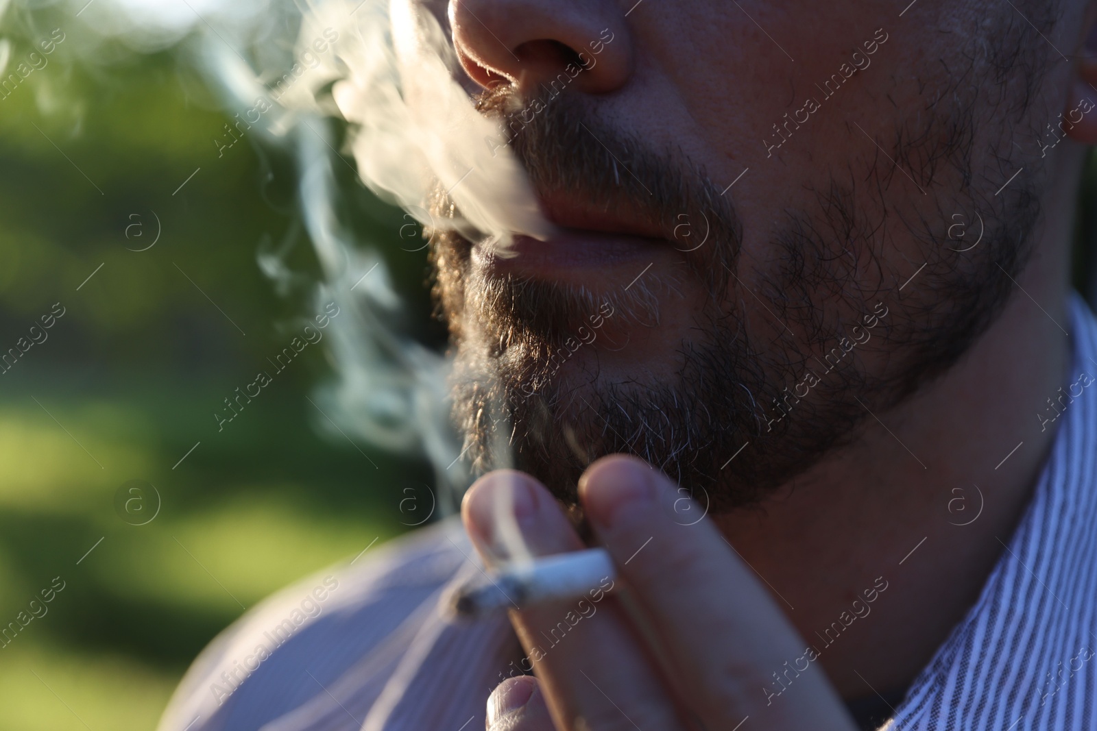 Man smoking cigarette on blurred background, closeup Photo of Man smoking cigarette on blurred background, closeup