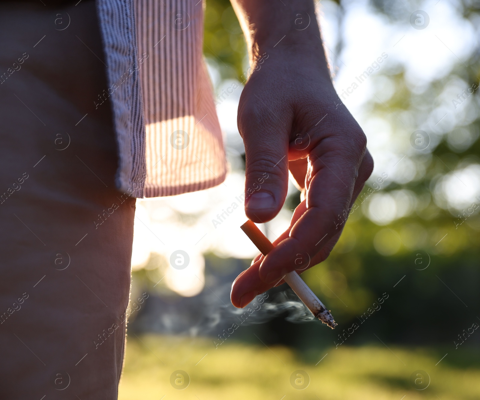 Man with cigarette in park, closeup view Photo of Man with cigarette in park, closeup view