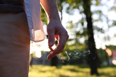 Photo of Man with cigarette in park, closeup. Space for text