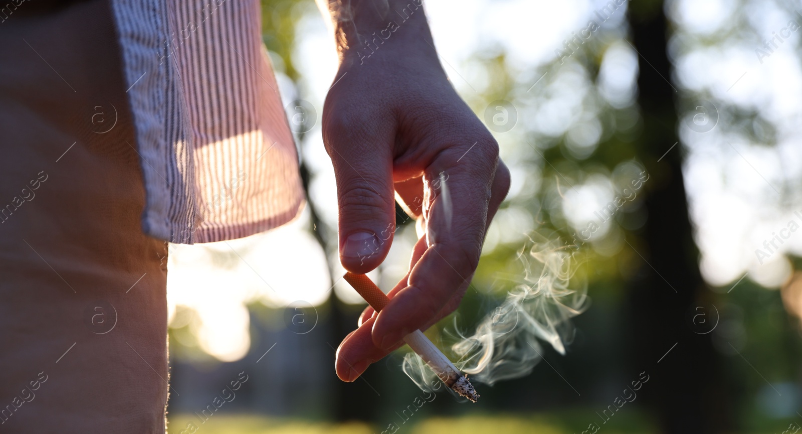 Man with cigarette in park, closeup. Space for text Photo of Man with cigarette in park, closeup. Space for text
