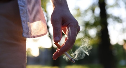 Photo of Man with cigarette in park, closeup. Space for text