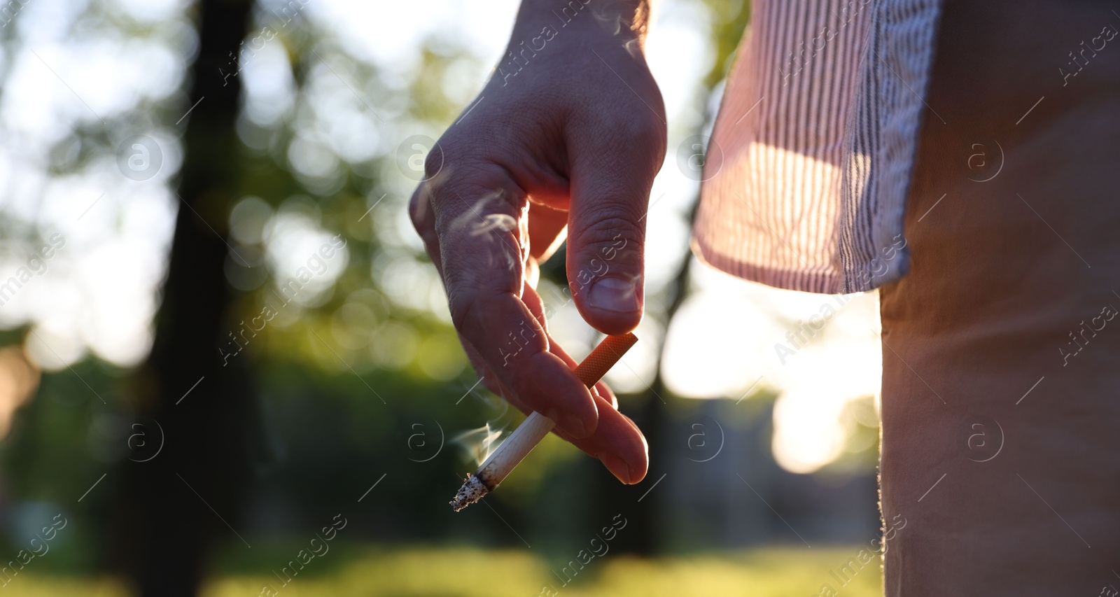 Man with cigarette in park, closeup. Space for text Photo of Man with cigarette in park, closeup. Space for text