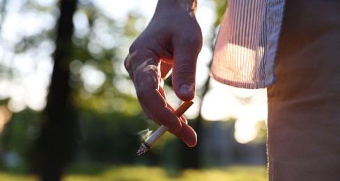 Photo of Man with cigarette in park, closeup. Space for text