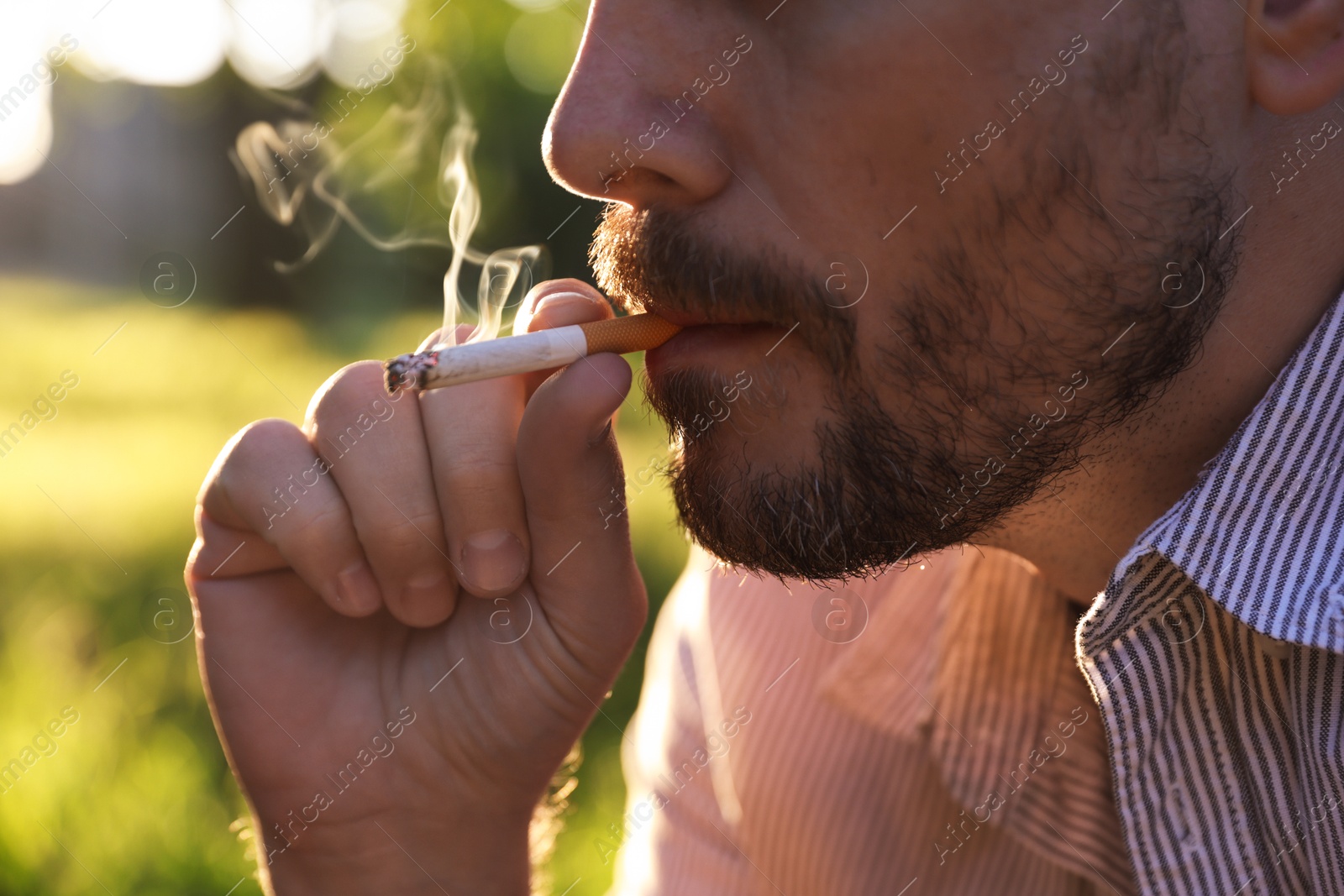 Man smoking cigarette on blurred background, closeup Photo of Man smoking cigarette on blurred background, closeup