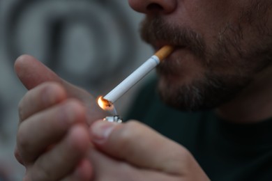 Photo of Man lighting cigarette on blurred background, closeup