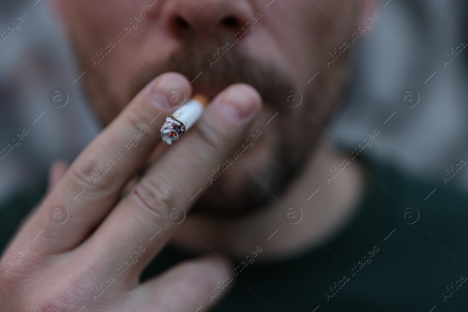 Man smoking cigarette on blurred background, closeup Photo of Man smoking cigarette on blurred background, closeup