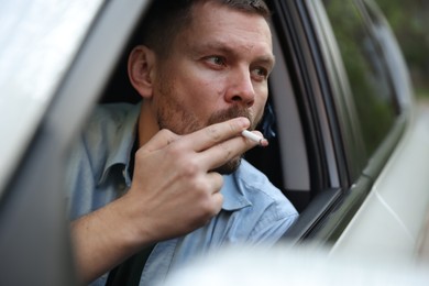 Photo of Man smoking cigarette in car, view from outside
