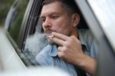 Photo of Man smoking cigarette in car, view from outside