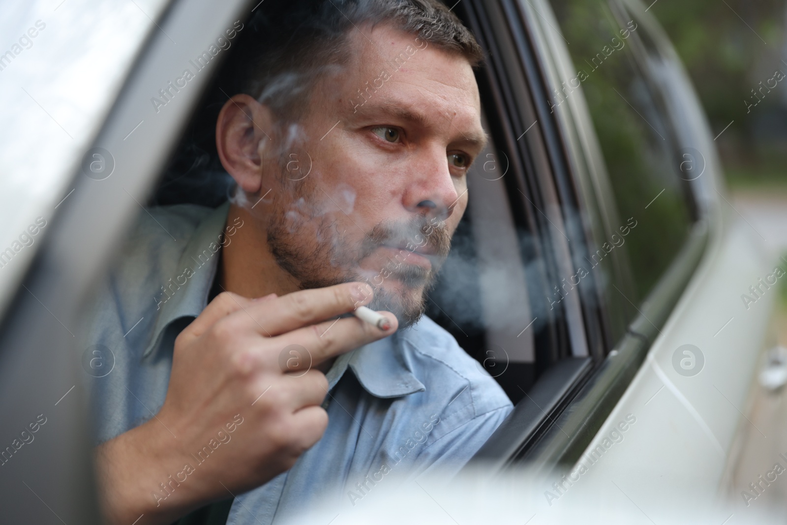 Man smoking cigarette in car, view from outside Photo of Man smoking cigarette in car, view from outside