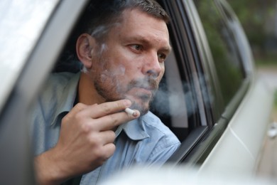 Photo of Man smoking cigarette in car, view from outside