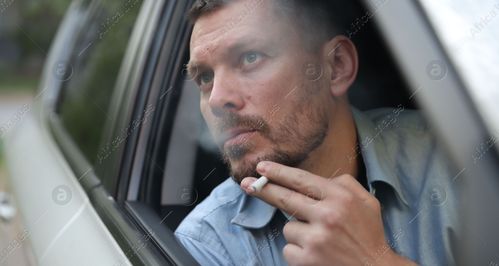 Man smoking cigarette in car, view from outside Photo of Man smoking cigarette in car, view from outside
