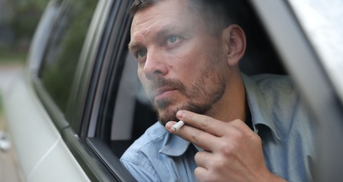 Photo of Man smoking cigarette in car, view from outside