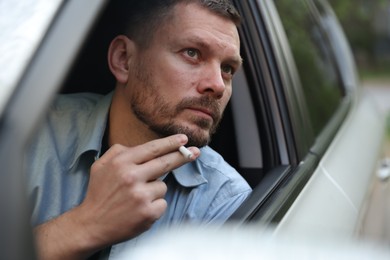 Photo of Man smoking cigarette in car, view from outside