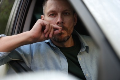 Photo of Man smoking cigarette in car, view from outside