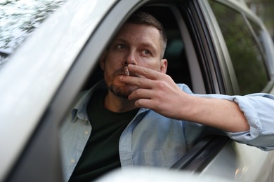 Photo of Man smoking cigarette in car, view from outside