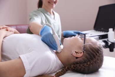 Photo of Sonographer conducting girl's thyroid gland ultrasound examination in clinic, closeup