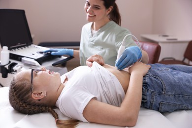 Photo of Sonographer conducting girl's abdominal ultrasound examination in clinic, closeup